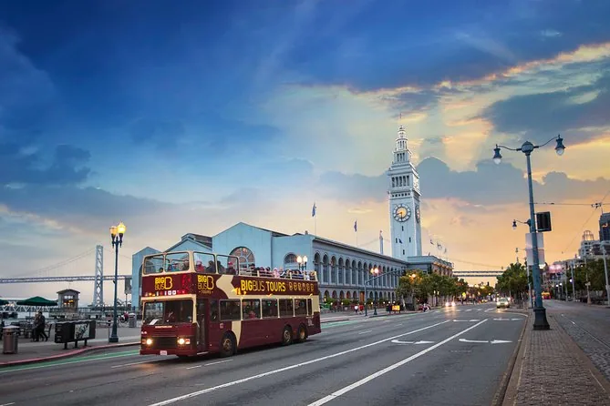 A red double-decker sightseeing bus on the Embarcadero near the Ferry Building at dusk