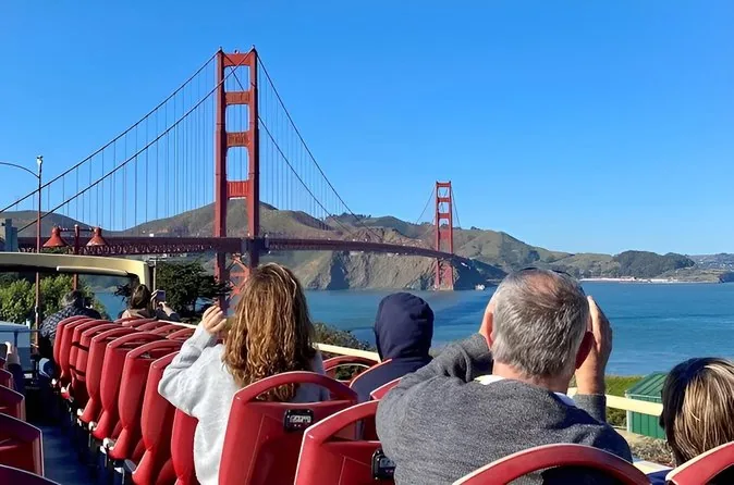 Fahrgäste auf dem offenen Oberdeck eines Sightseeing-Busses mit Blick auf die Golden Gate Bridge